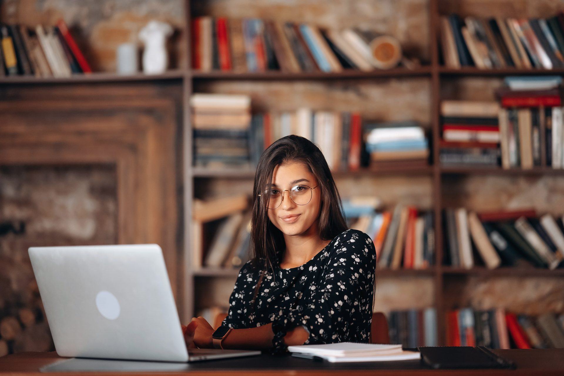Research scholar at a laptop in front of full library bookshelves